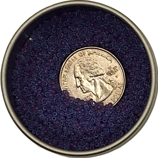 Purple-lined aqua seed beads in a tin with a quarter for size comparison.