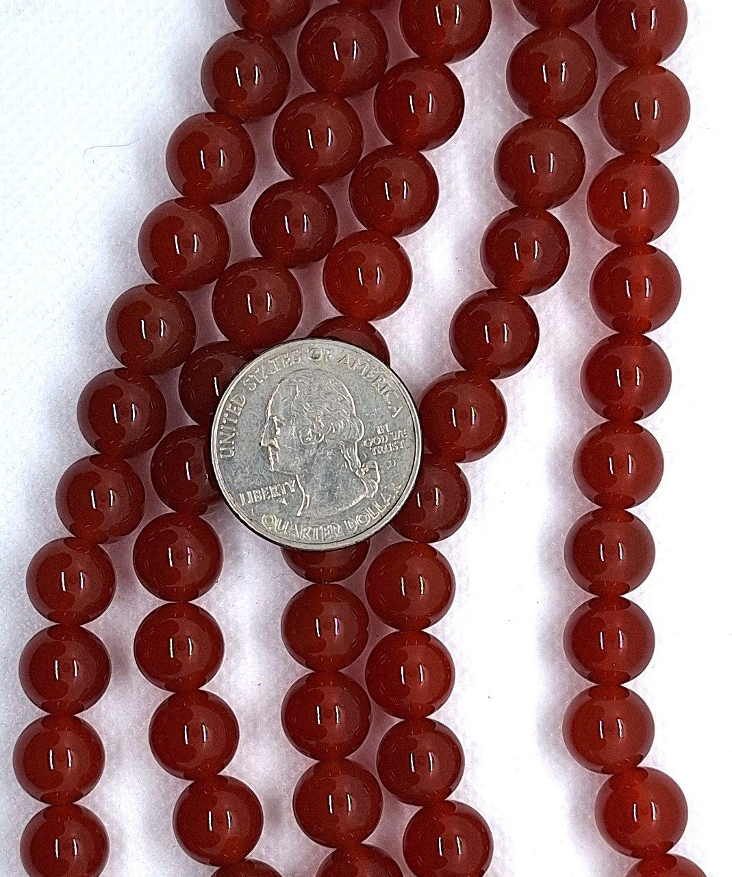 Red orange beads with a silver coin in the center on a white background