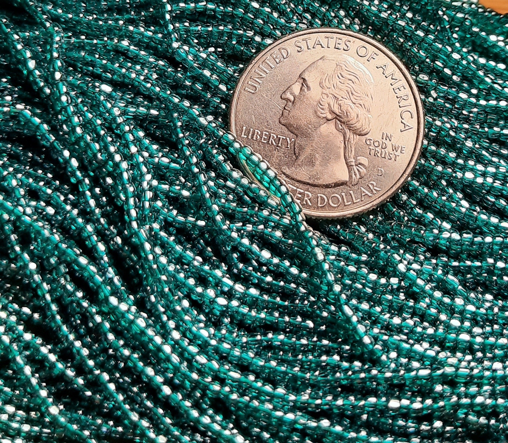 A strand of blue zircon transparent luster 3-cut Czech seed beads, with a coin for size comparison.