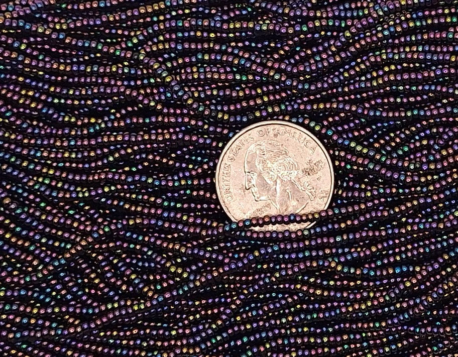 Close-up of a coin as size comparison for a field of metallic purple iris seed beads.