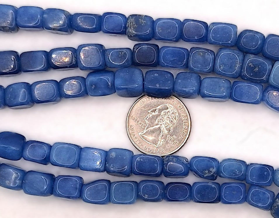 Blue rectangular stone beads with rounded corners, shown in multiple strands on a white background with a coin for scale.