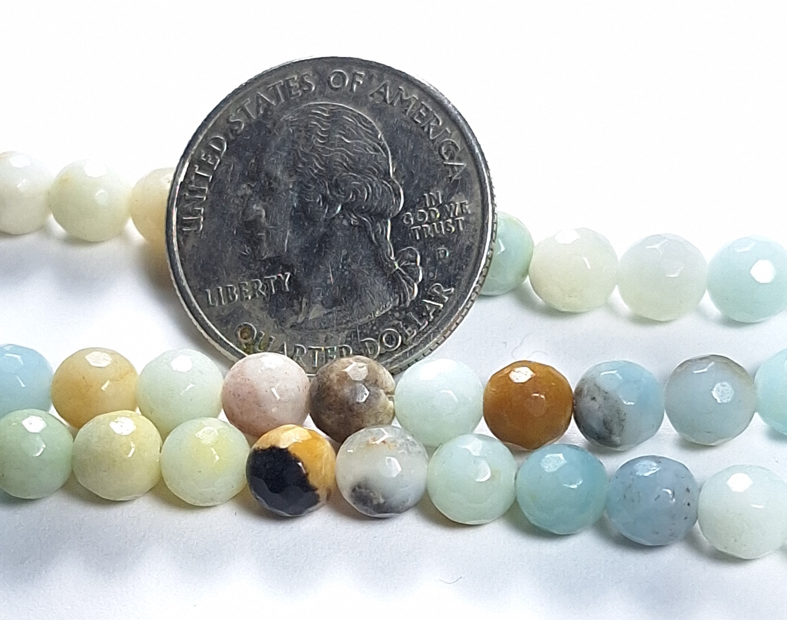 Strand of multicolor amazonite faceted round gemstone beads, with a coin for scale.