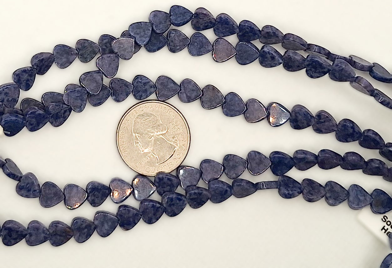 Three strands of blue heart-shaped beads with a coin for scale on a white background