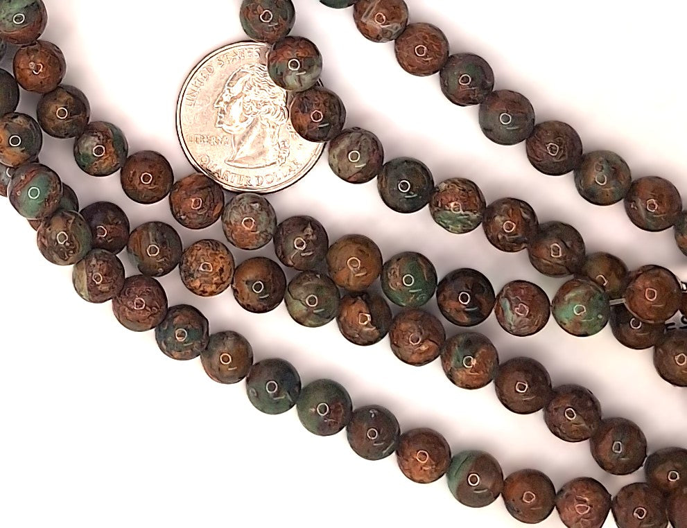 A close-up of a strand of round brown and green marbled beads, with a US quarter coin placed in the center for scale, on a plain white background.